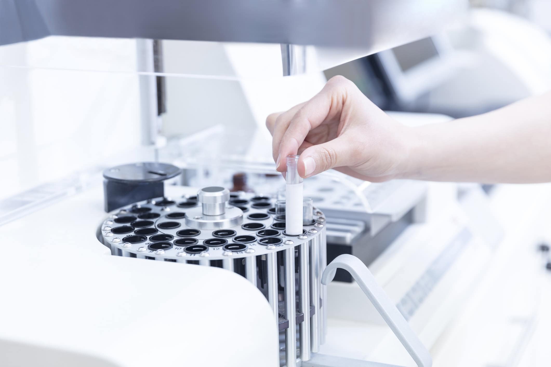 hand holding a test tube being put into a Centrifuge